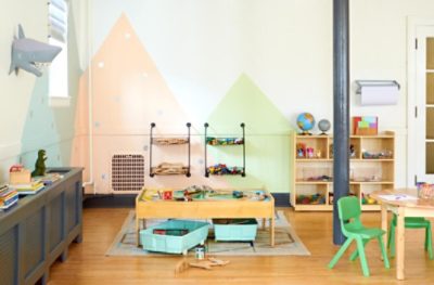 Neutral walls in a child's playroom painted with a colorful mountain mural.